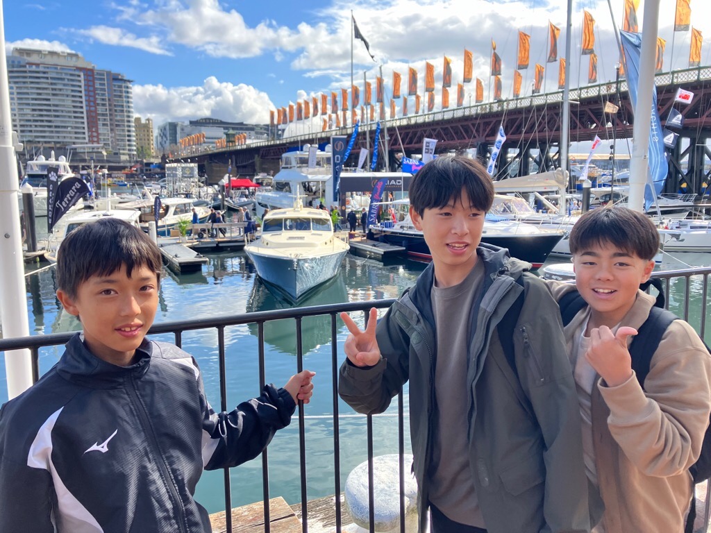 港にある船を背景にした学生3人の写真