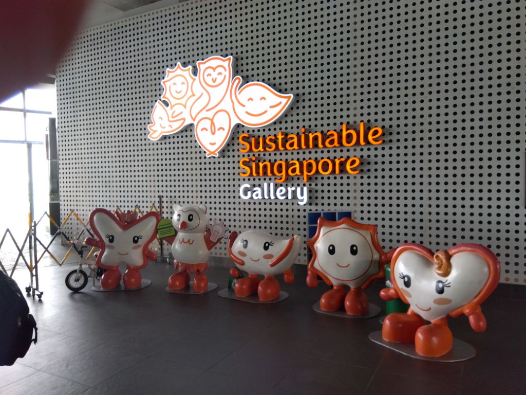 壁に「Sustainable Singapore Gallery」と書かれ、前にマスコットキャラクターが並んでいる写真