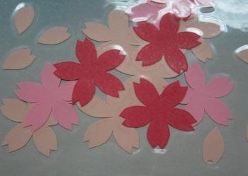 白やピンクの桜の花や花弁を形どったペーパークラフトの切り絵の写真