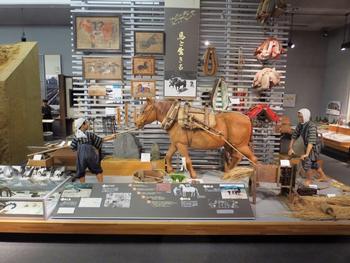 絵や縄など馬に関する資料と、馬を使った代かきを再現した展示の写真
