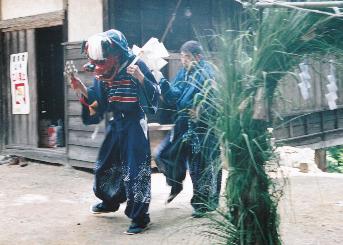 茅でできた大きな輪の前で神楽舞を踊る二人の男性