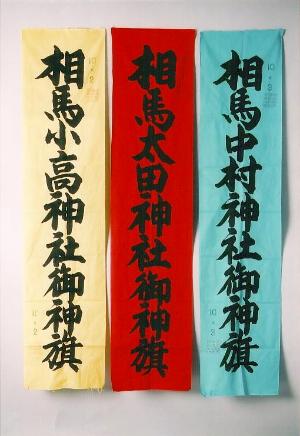 左から相馬小高神社と書かれた黄色の旗、相馬太田神社と書いた赤い旗、相馬中村神社と書いた青い旗