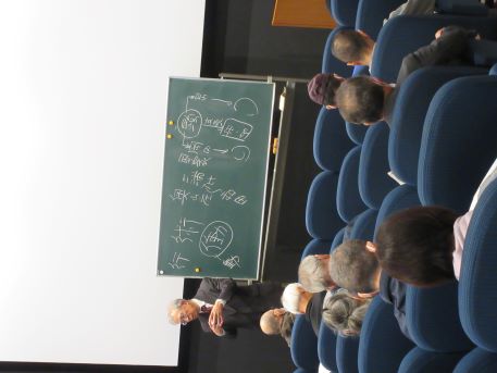 黒板の前で解説する講師とそれを聴く参加者たち