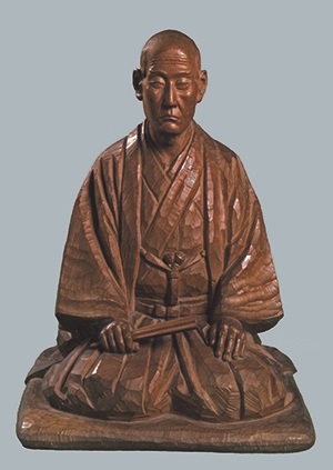 富田高慶が座っている木彫りの像の写真
