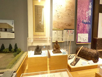 南相馬市博物館展示室の歴史の展示。中央にケースに入った人物彫刻が2点置かれている。
