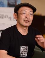 メガネとハンチング帽をかぶった越川道夫監督のバストショットの写真