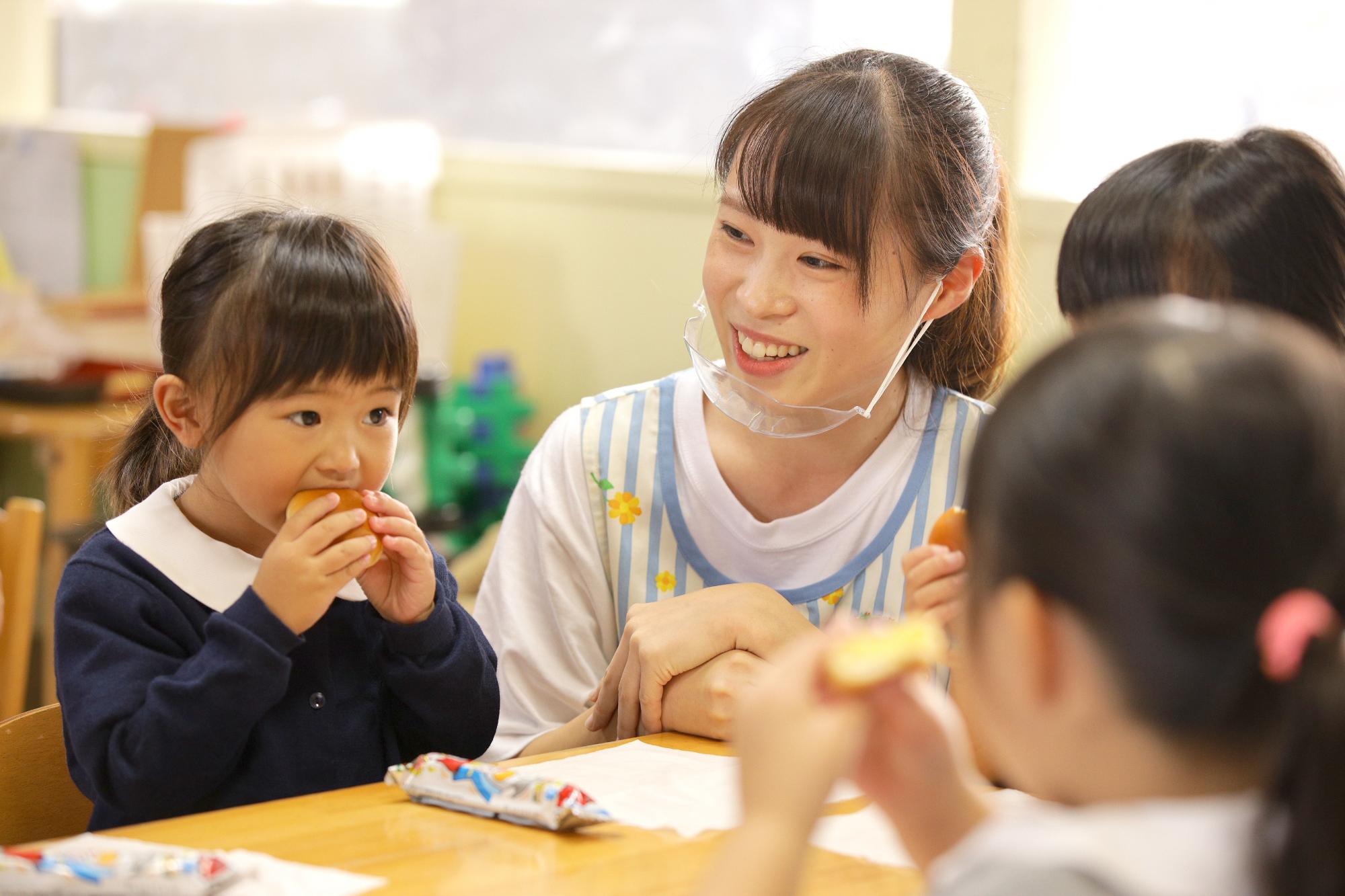 幼稚園で園児と一緒におやつの時間を過ごす小林さん