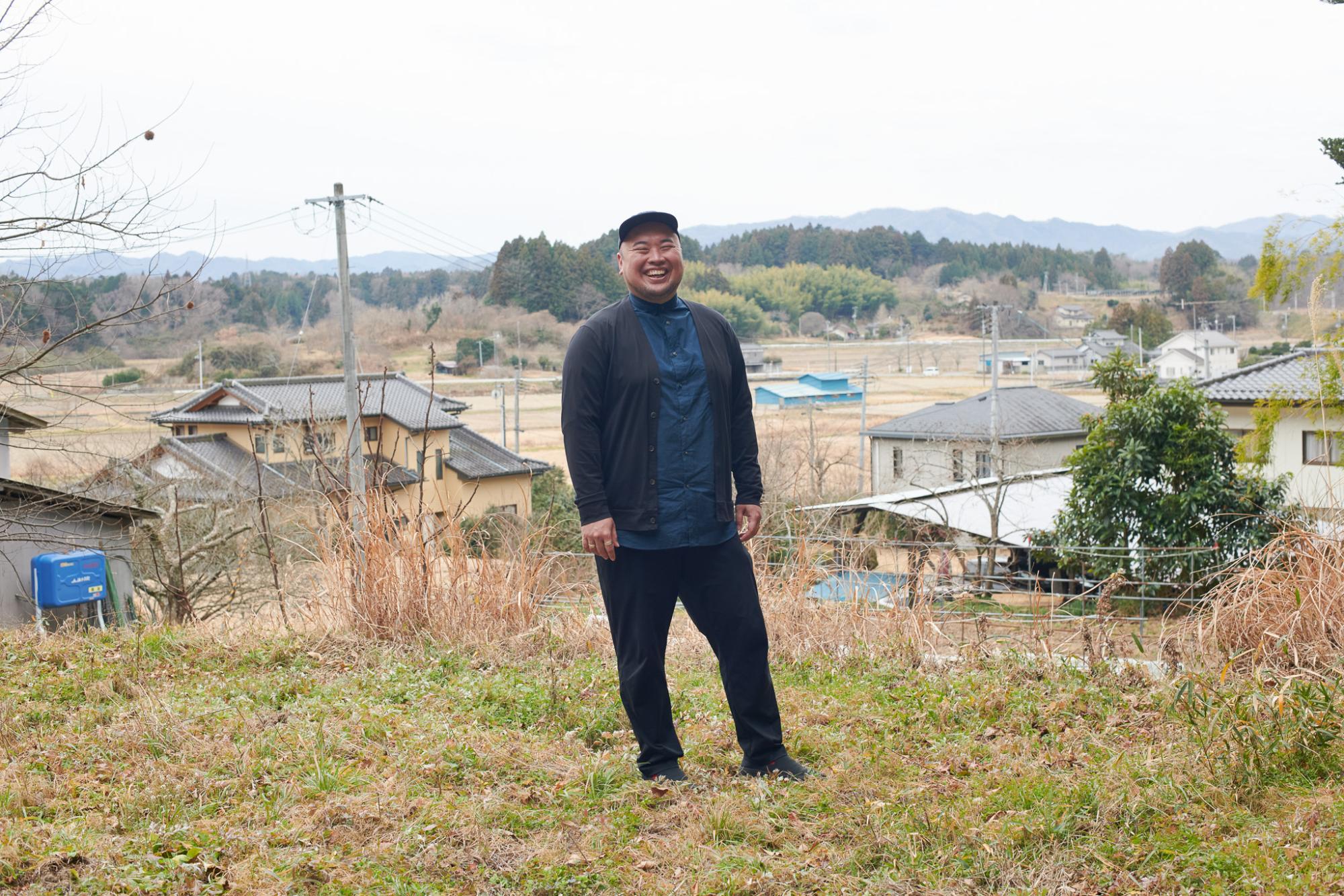 自然を背景に笑顔の小波津さん