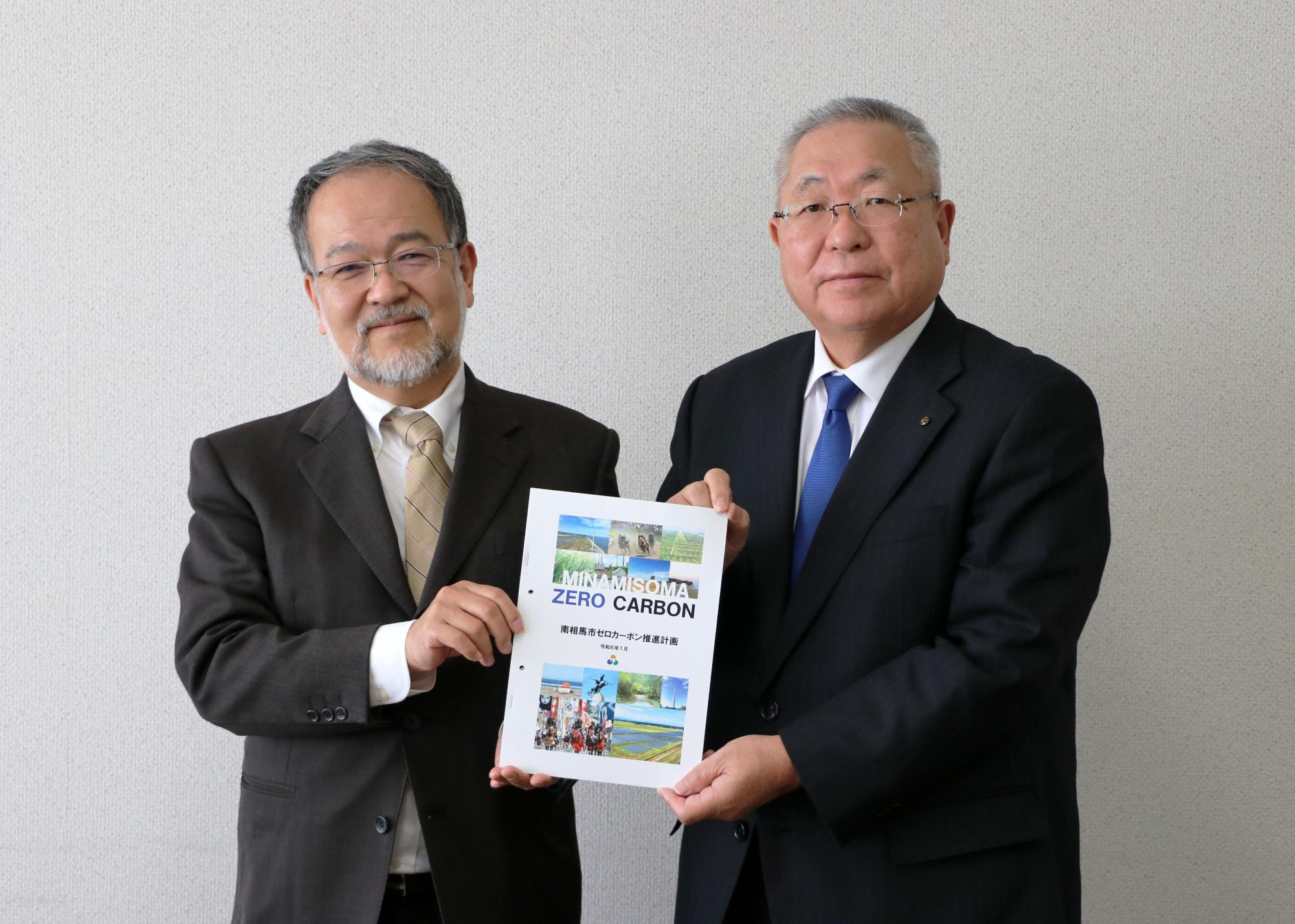 委員長と市長（正面）が計画の冊子を手に持っている写真